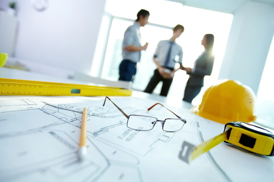 Réunion de travail dans un bureau moderne avec trois professionnels en discussion debout près d'une fenêtre