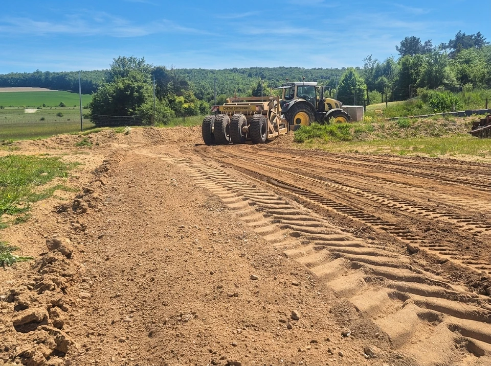 Chantier de terrassement en extérieur avec pelleteuse hydraulique orange opérant sur terrain rocheux près d'un plan d'eau